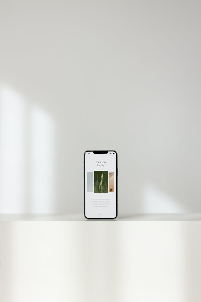 A sleek smartphone displaying a modern website, on a white shelf with a serene background.