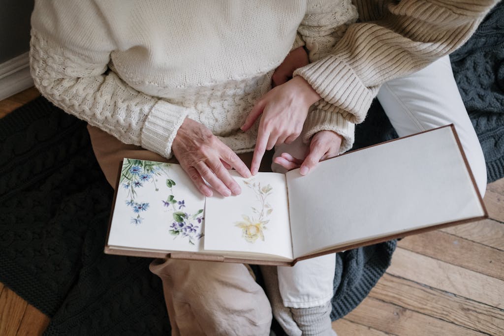 Close-up of hands turning pages in a floral photo book, symbolising shared remembrance